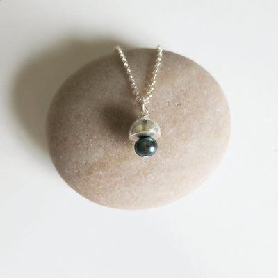 Necklace with a green bead pendant on a stone surface