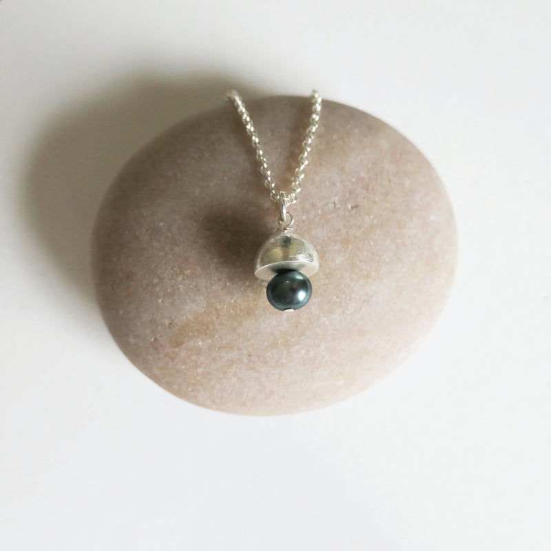 Necklace with a green bead pendant on a stone surface